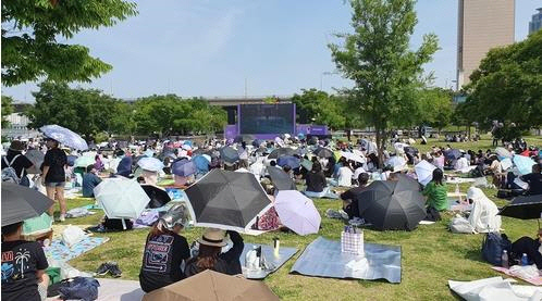 17일 서울 여의도 한강공원에서 열린 'BTS 10th 애니버서리 페스타'에서 팬들이 전광판 앞에 앉아 방탄소년단의 음악을 즐기고 있다. 연합뉴스